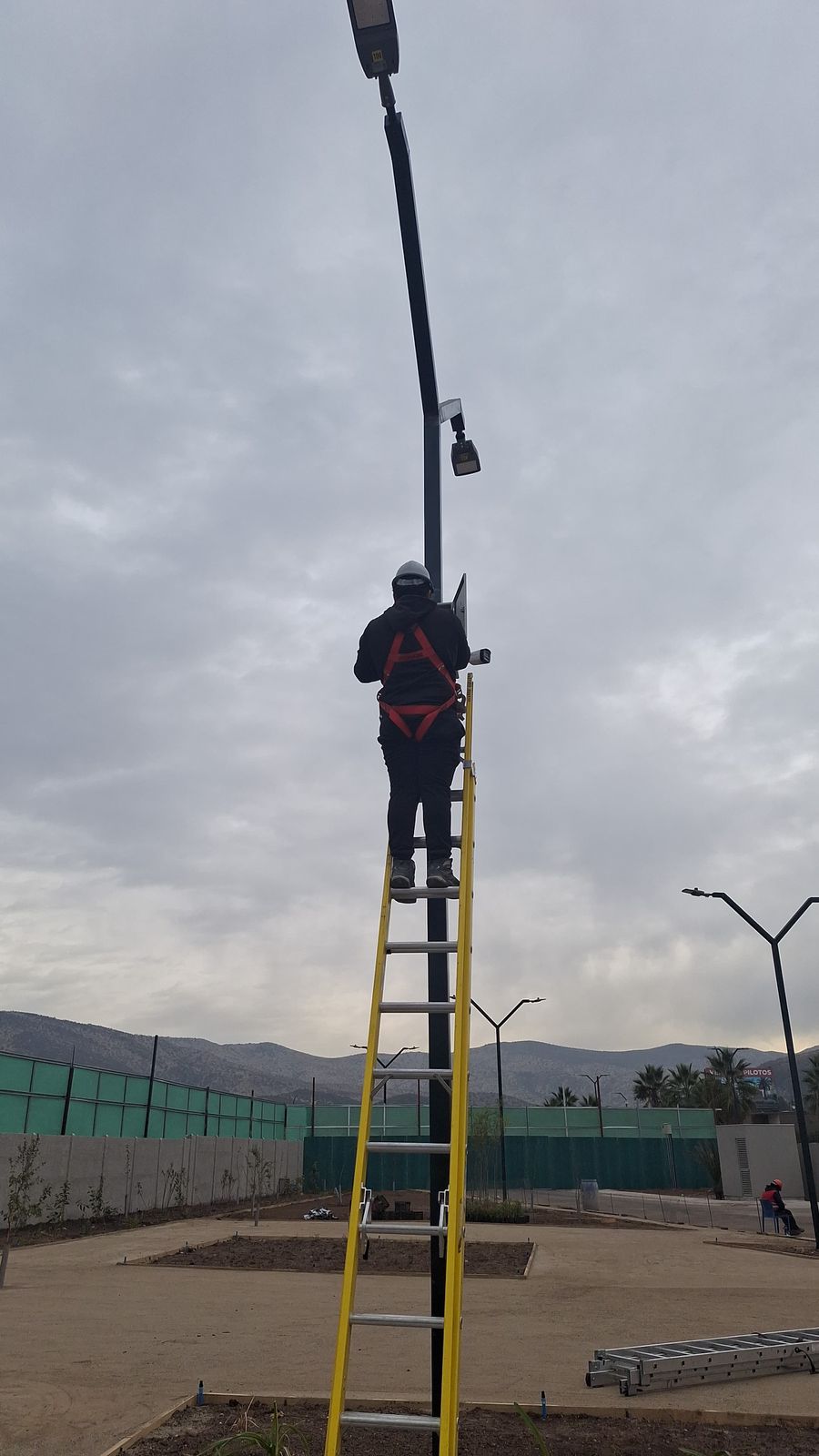 Técnico con arnés de seguridad realizando instalación de gabinete en altura